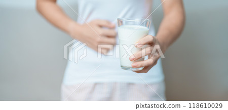 Lactose intolerance and Milk allergy concept. woman hold Milk glass and having abdominal cramps and pain when drink Cow Milk. Symptom stomach ache, Dairy intolerant, Nausea, Bloating, Gas and Diarrhea 118610029