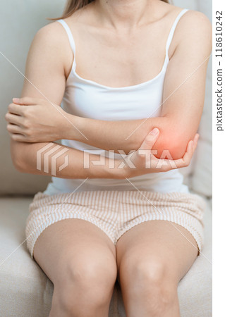 Woman having elbow ache at home, muscle pain due to lateral epicondylitis or tennis elbow. injury, Health and medical concept 118610242
