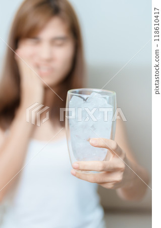 Teeth Sensitive to Cold concept. woman hold Ice Water glass and having toothache and pain after eat. Tooth Decay or Gum Disease, Grinding Teeth and Stress, Exposed Nerve Roots, Crack and Receding Gums 118610417