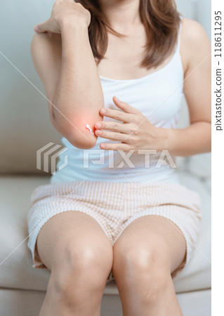 Arthritis and Muscle Pain Relief Cream concept. Woman having elbow ache at home, muscle pain due to lateral epicondylitis or tennis elbow. injury, Health and medical concept Arthritis and Muscle Pain Relief Cream concept. Woman having elbow ache at home, muscle pain due to lateral epicondylitis or tennis elbow. injury, Health and medical concept 118611295