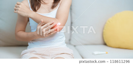 Arthritis and Muscle Pain Relief Cream concept. Woman having elbow ache at home, muscle pain due to lateral epicondylitis or tennis elbow. injury, Health and medical concept Arthritis and Muscle Pain Relief Cream concept. Woman having elbow ache at home, muscle pain due to lateral epicondylitis or tennis elbow. injury, Health and medical concept 118611296