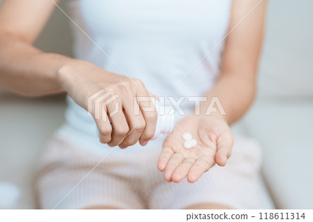 woman hand holding medicine painkiller pill on the sofa at home, taking for headaches, stomach ache, Diarrhea Pain from food poisoning, Endometriosis, Hysterectomy and Menstrual 118611314