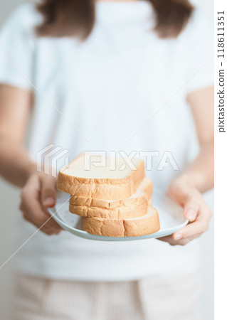 Bread eating and Daily Routine concept. Young woman Hand holding sliced whole grain bread in the morning at home Bread eating and Daily Routine concept. Young woman Hand holding sliced whole grain bread in the morning at home 118611351