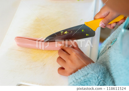 A 10-year-old boy's hands cutting fish sausage with a child's knife A 10-year-old boy's hands cutting fish sausage with a child's knife 118611524