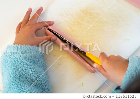 一名10歲男孩用兒童刀切魚香腸。 一名10歲男孩用兒童刀切魚香腸。 118611525