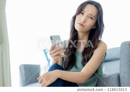 Woman looking at smartphone on sofa Negative Woman looking at smartphone on sofa Negative 118613013