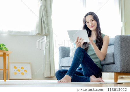 Woman looking at tablet in living room Woman looking at tablet in living room 118613022