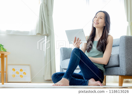 Woman looking at tablet in living room 118613026
