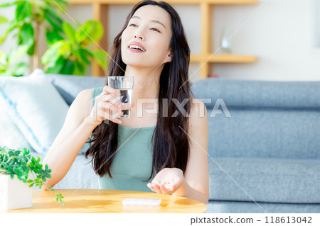 A young woman drinking supplements in the living room 118613042