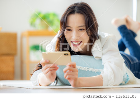 A woman watching a video on a smartphone 118613103