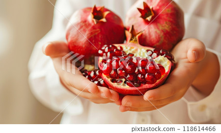 Fresh pomegranates and seeds held in hands highlighting natural abundance and vibrant color 118614466