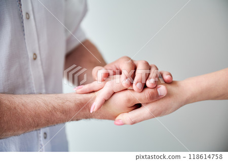 Close up of two hands engaging in delicate touch. Man's and woman's hands on white neutral background. Husband holding hand of his lovely wife. Concept of love, intimacy, support, and trust. 118614758