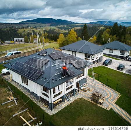 Professional engineers installing solar battery on a roof of big wooden house. Drone view of solar panels installation in mountains. Green electricity concept. 118614766