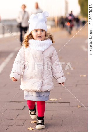 Little funny girl runs and smiles on yellow trees background in the autumn park. Preschool girl running and laughing on the park alley 118615018