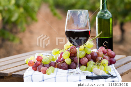 Glass of red wine and ripe grapes on table 118615628