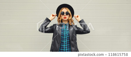 Beautiful stylish young woman posing in black round hat, leather jacket, glasses on city street Beautiful stylish young woman posing in black round hat, leather jacket, glasses on city street 118615758