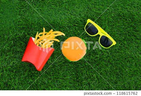 Fast food concept - burger, french fries and sunglasses on the grass background Fast food concept - burger, french fries and sunglasses on the grass background 118615762