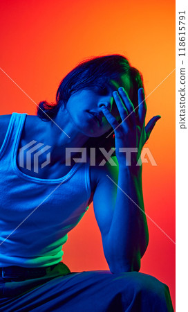 Posing in blue neon light young man showing himself through poses against gradient studio background. Uniqueness. Posing in blue neon light young man showing himself through poses against gradient studio background. Uniqueness. 118615791