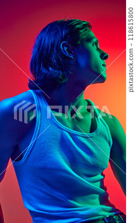 Portrait in blue neon light of young attractive man with long hair dressed casual outfit against gradient studio background. 118615800