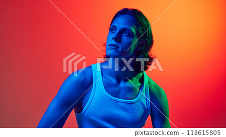 Confident, stylish young man looking thoughtfully upwards in blue neon light against gradient studio background. Confident, stylish young man looking thoughtfully upwards in blue neon light against gradient studio background. 118615805