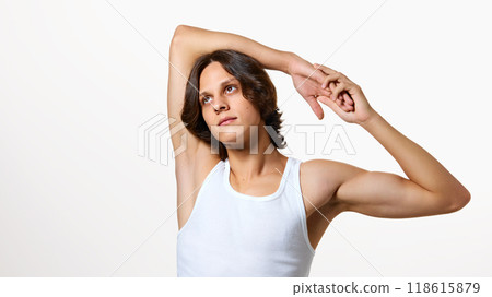 Calm young man stretching his hands and looking upwards against white studio background. Morning exercises. Calm young man stretching his hands and looking upwards against white studio background. Morning exercises. 118615879
