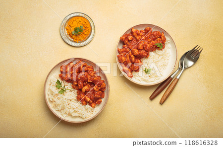 Indian chicken curry served with white rice and turmeric on yellow background top view 118616328