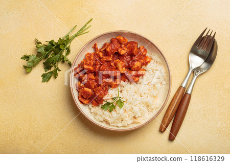 Indian chicken curry served with white rice and turmeric on yellow background top view Indian chicken curry served with white rice and turmeric on yellow background top view 118616329