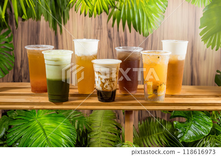 taiwan style boba Iced coffee drinks in plastic cups on wooden shelf with tropical leaves background 118616973