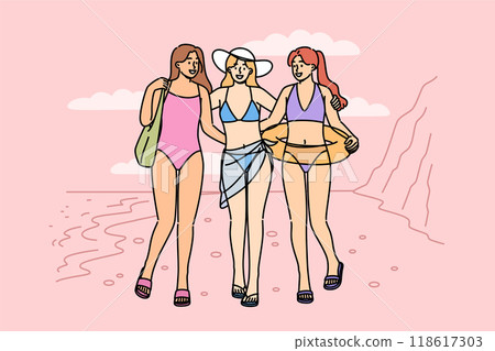 Women in bikinis walk along beach on seashore, enjoying summer holiday at hot resort 118617303