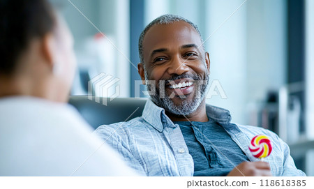 Smiling Man Holding a Lollipop in a Joyful Moment Smiling Man Holding a Lollipop in a Joyful Moment 118618385