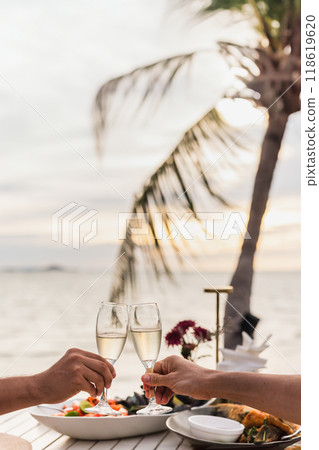 Couple toasting glass of  Champagne at dinner table on teh beach. 118619620