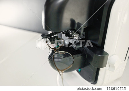 Focus on a special optical equipment. Optician checking eyeglasses in special machine. New ophthalmological technology. Focus on a special optical equipment. Optician checking eyeglasses in special machine. New ophthalmological technology. 118619715