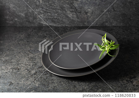 Empty round black plates with rosemary on a black stone background. Empty round black plates with rosemary on a black stone background. 118620833