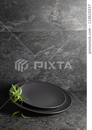 Empty round black plates with rosemary on a black stone background. Empty round black plates with rosemary on a black stone background. 118620837