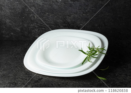 Empty white plates with rosemary on a black stone background. Empty white plates with rosemary on a black stone background. 118620838