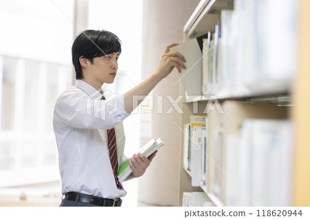 高中男孩在圖書館選擇一本書 118620944