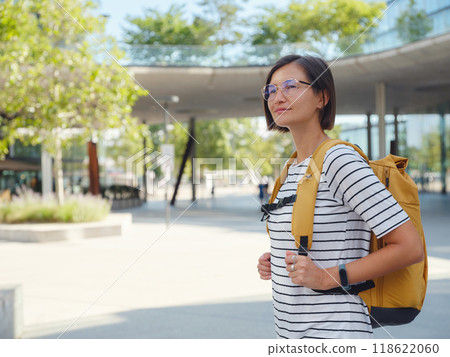 Asian woman with yellow backpack over background of modern urban architecture in Vienna. charming pensive female hipster admire cityscape of modern Vienna city 118622060
