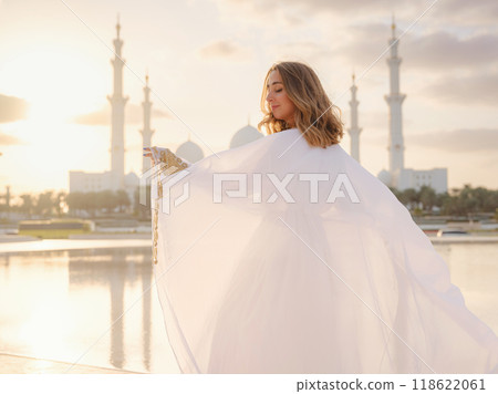 Travel to the United Arab Emirates, Abu Dhabi. Woman in white Arabic dress looking at Sheikh Zayed Great white mosque. famous Abu Dhabi sightseeing. 118622061