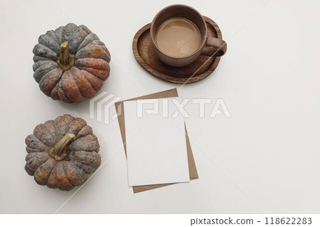 Autumn stationery. Empty greeting card, invitation envelope mockup. Cup of coffee, pumpkins isolated on white table background. Linen tablecloth. Fall Thanksgiving, Halloween holiday flatlay, top view 118622283