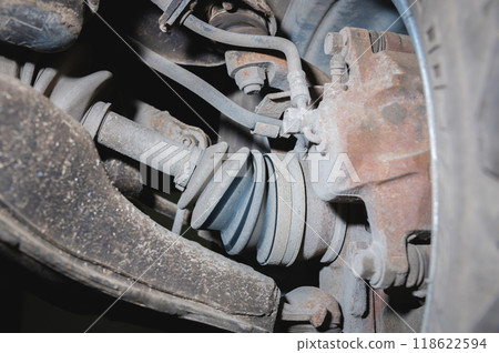 View from inside dirty used suspension of front-wheel drive car. Angle on CV joint with semi-drive and brake caliper 118622594