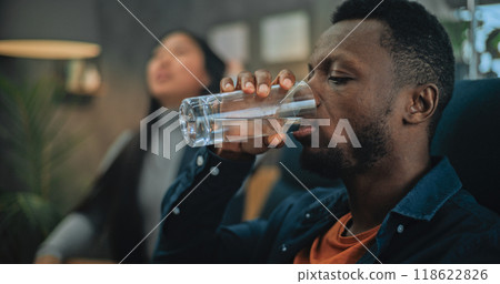 Close up of annoyed African American man drinking water during couples therapy 118622826
