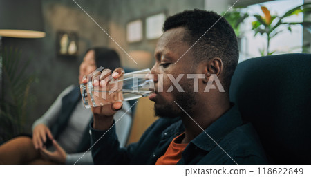 Close up of annoyed African American man drinking water during couples therapy 118622849