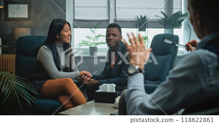 Happy multiethnic couple sit on chairs hand in hand on couples therapy 118622861