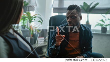 Aggressive man shouts at his girlfriend on counseling session with family psychotherapist Aggressive man shouts at his girlfriend on counseling session with family psychotherapist 118622923