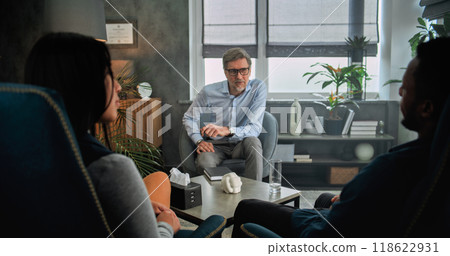 Mature psychotherapist talks to young family, provides couples therapy 118622931