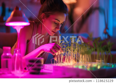 Young woman watching illuminated smart microgreens farm at home 118623229