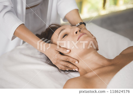 Therapists hands massage female head, close-up. Woman lying on back in pro salon, selective focus. 118624576