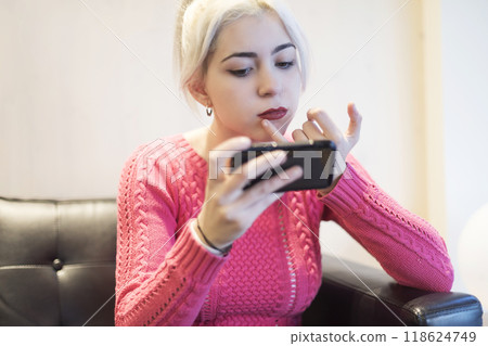 Focused young woman using smartphone in cozy setting 118624749