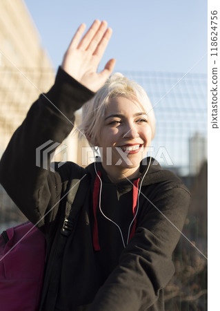 Joyful young woman waving in the sunlight Joyful young woman waving in the sunlight 118624756