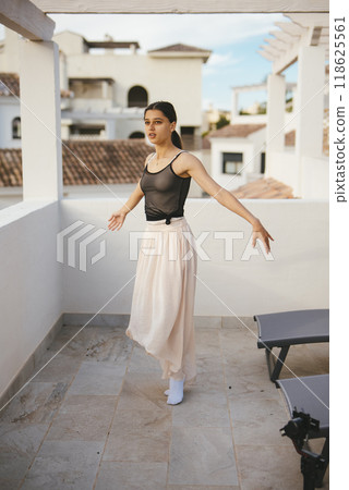 A Graceful Ballet Pose Captured on a Rooftop Terrace Against a Beautiful Skyline A Graceful Ballet Pose Captured on a Rooftop Terrace Against a Beautiful Skyline 118625561